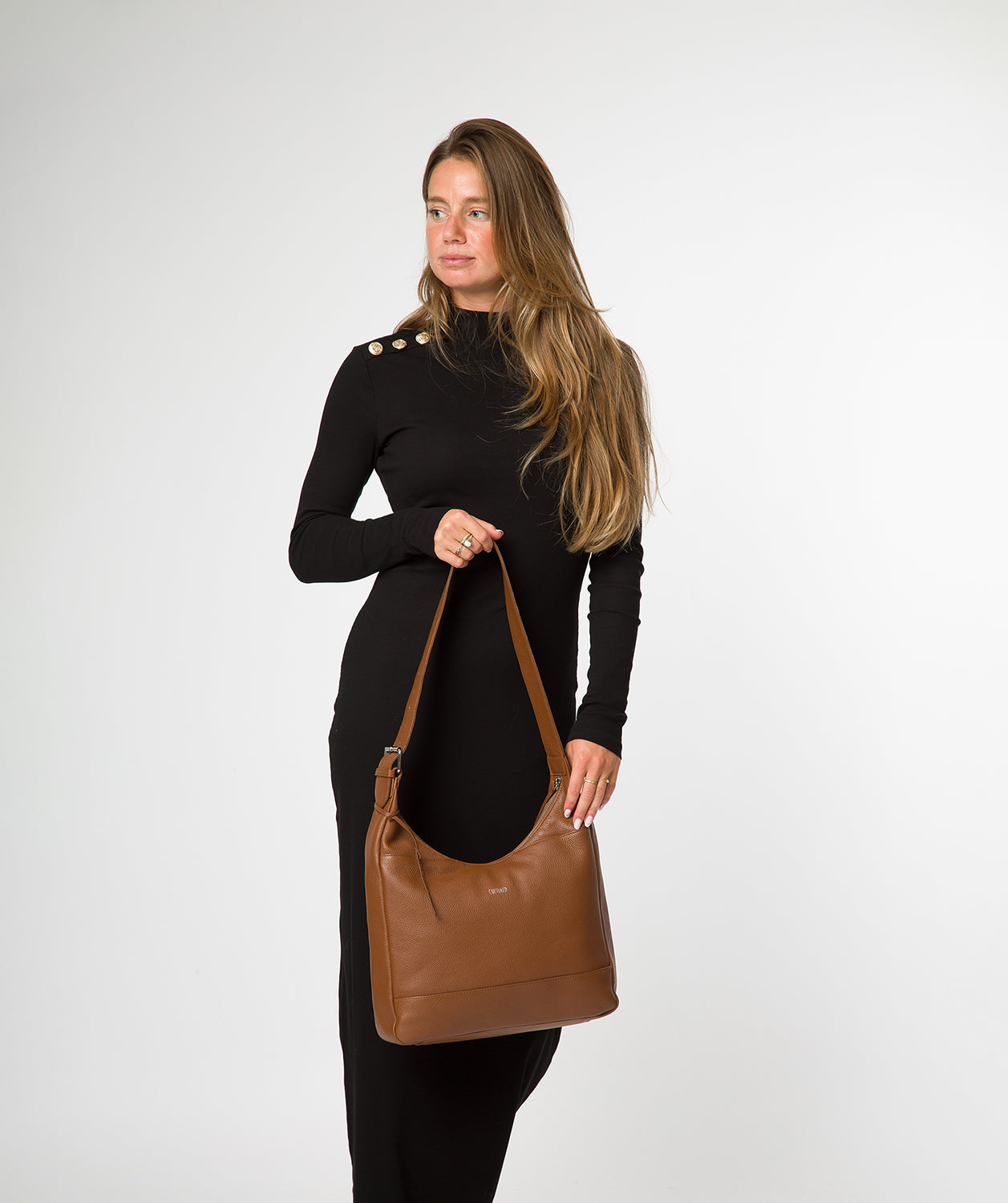 Crescent zip-over closure detail on tan leather bag
